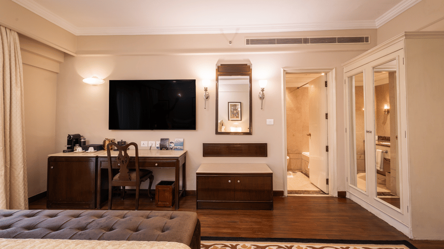 image of the heritage terrace room with a wall mounted tv and a half length mirror - The Claridges New Delhi