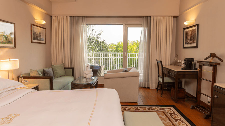 image of the king sized bed with french windows at the far end of the room at our heritage balcony room - The Claridges New Delhi