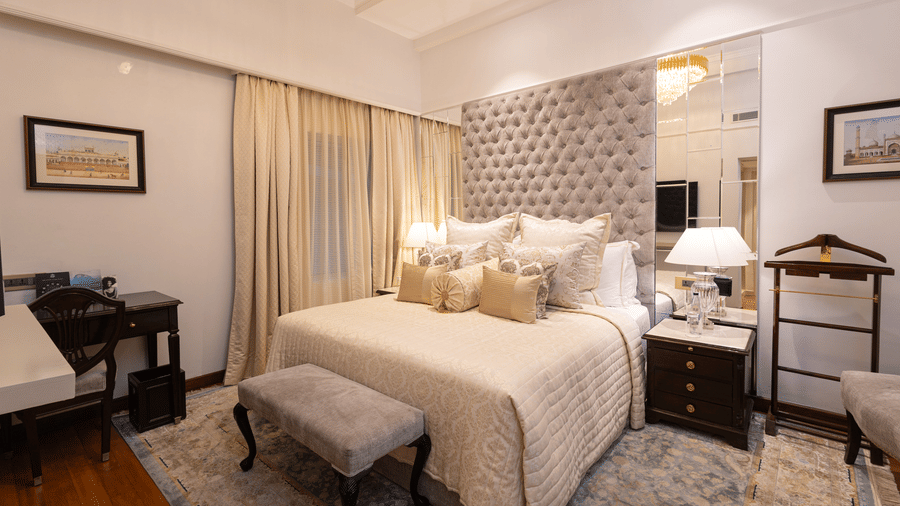 image of the boutique room featuring the king size bed with a small cushioned stool in front of it - The Claridges New Delhi