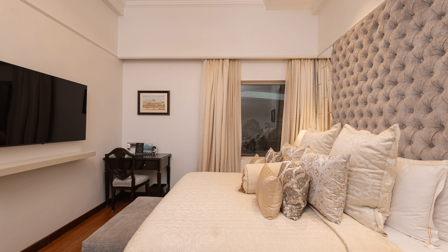 image of a king size bed with well set pillows over at our boutique room with a wall mounted tv - The Claridges New Delhi