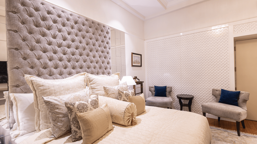 a side angle view of the boutique room with a well decorated king size bed and two cushioned chairs in the background - The Claridges New Delhi
