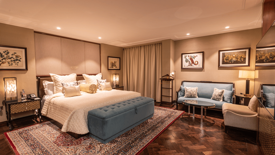 a full view image of the cabana room in its full grandeur featuring the king size bed and the seating area along with elegant interiors throughout - The Claridges New Delhi 