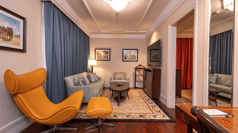 image of the living room with a yellow arm chair and a couch at our regent suite - The Claridges New Delhi