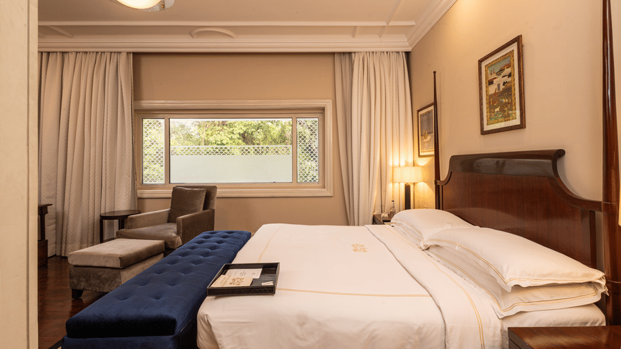 image of a heritage room bedroom with soft king sized bed and a wide window - The Claridges New Delhi