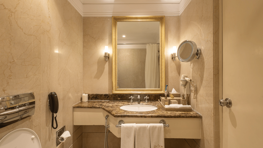 image of the sink with a rectangular mirror above it at our heritage balcony room -image of the heritage balcony room with sleek interiors and a a plush king size bed - The Claridges New Delhi