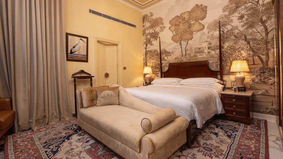 image of a bedroom at our heritage room with a brown scale wallpaper with lush trees - The Claridges New Delhi 
