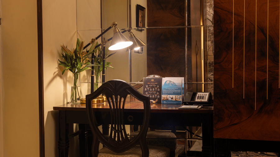 an image of the work desk with a table lamp providing light on the table at our heritage room - The Claridges New Delhi