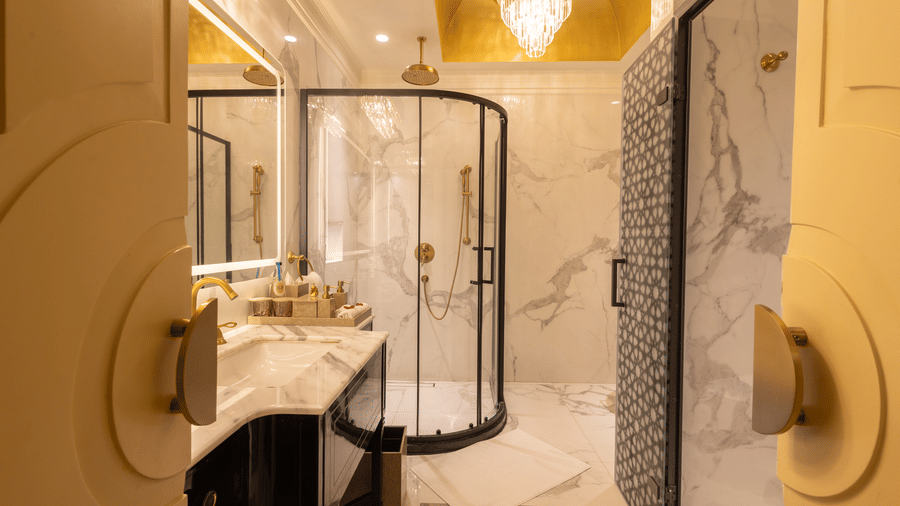 image of the bathroom attached to the heritage room featuring a cubical shower and a chandelier on top - The Claridges New Delhi