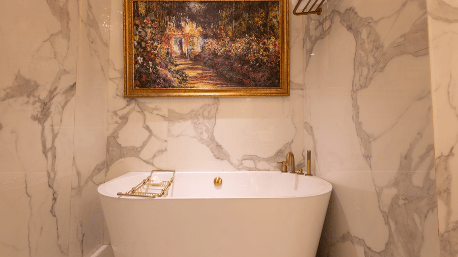 image of the white ceramic bathtub with an amazing golden frame above it - The Claridges New Delhi