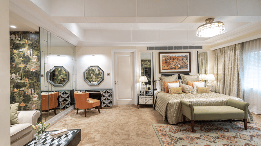 image of our willingdon crescent suite with a king sized bed and a bureau with an orange coloured cushioned chair - The Claridges New Delhi 