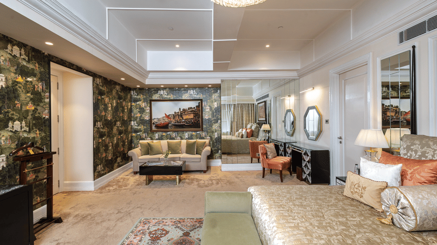 image of our willingdon crescent suite with a three seater couch at the far end of the room along with a full lenght mirror - The Claridges New Delhi