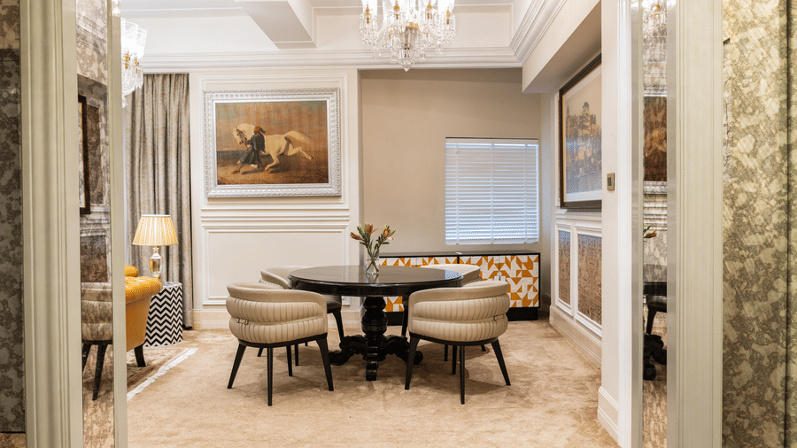 image of a dining table with four cushioned chairs places around the table in a brightly lit area in our willingdon crescent suite - The Claridges New Delhi