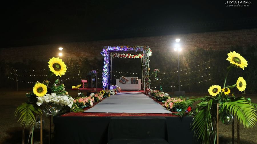 Stage setup with floral decor and lighting at night at Tisya Farms, Gurgaon.
