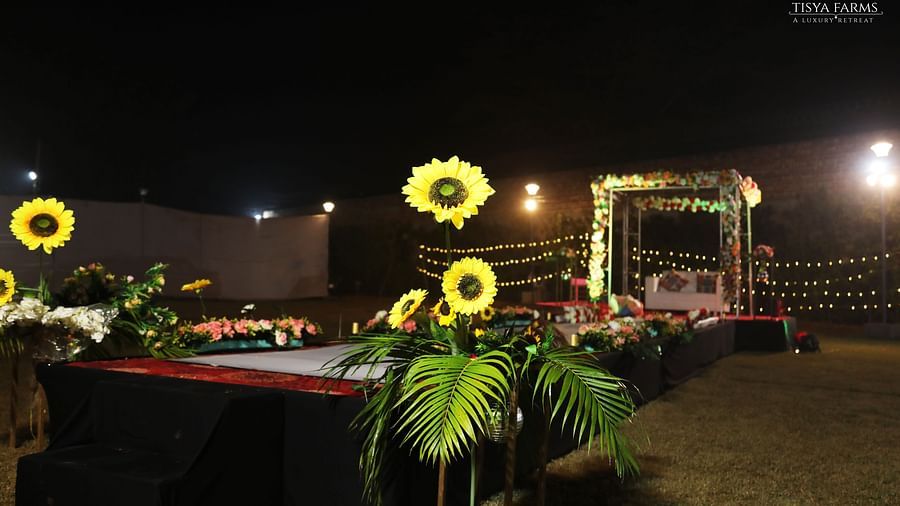 Stage setup with floral decor and lighting at night at Tisya Farms, Gurgaon.