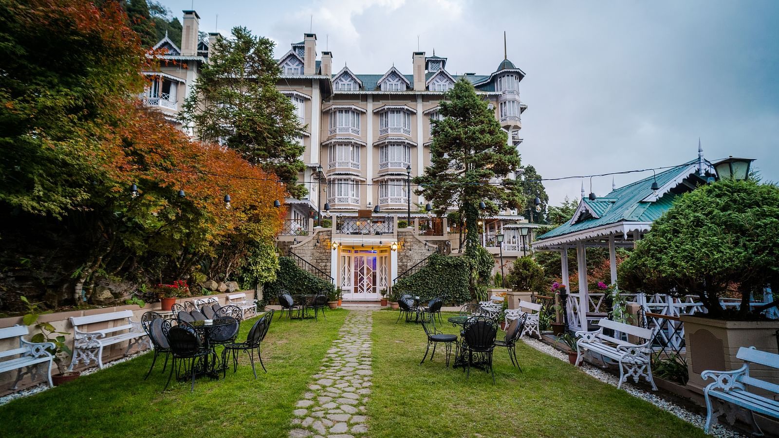 Stoned pathway in the lawn of Cedar Inn, Darjeeling leading to the hotel featuring a colonial architecture and multi-storey stature.
