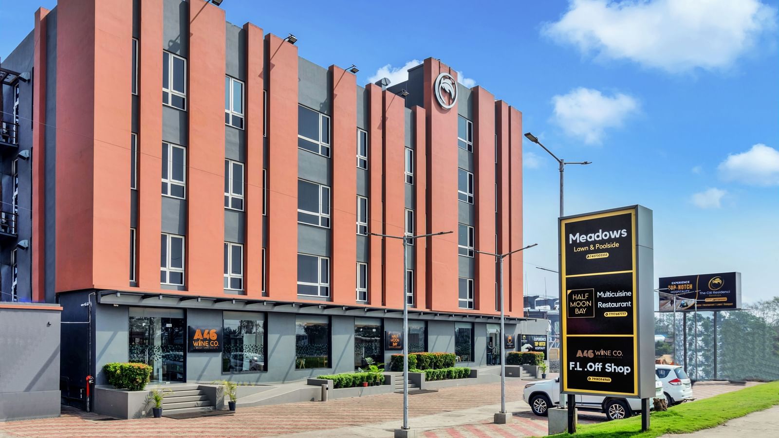 A modern, multi-story hotel building with orange and grey facade under a blue sky with scattered clouds  | The Citi Residenci Hotel Banskopa
