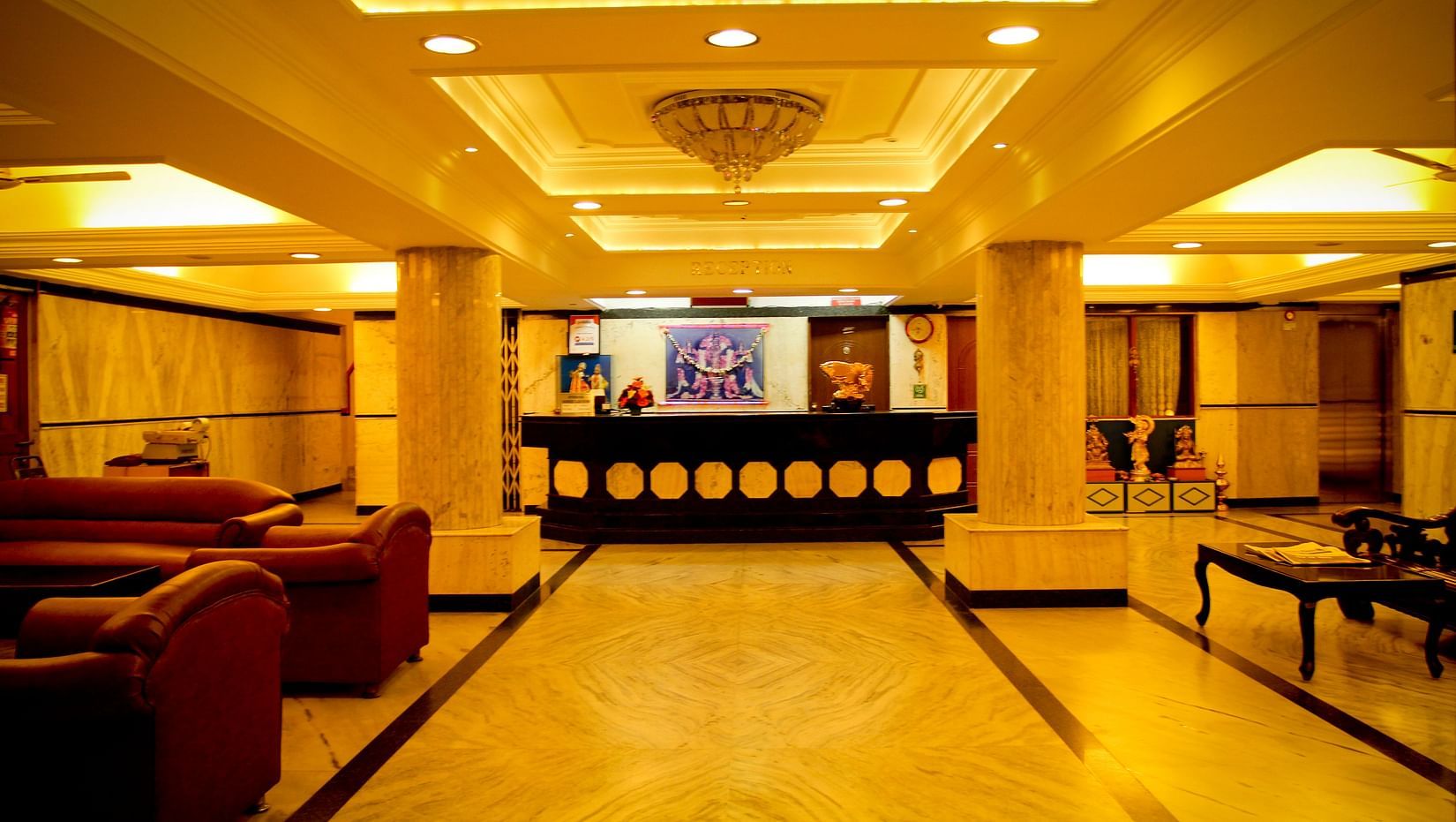  Hotel Yasodha Towers - Interior view of the lobby area featuring supporting pillars and sofas in yellow lighting