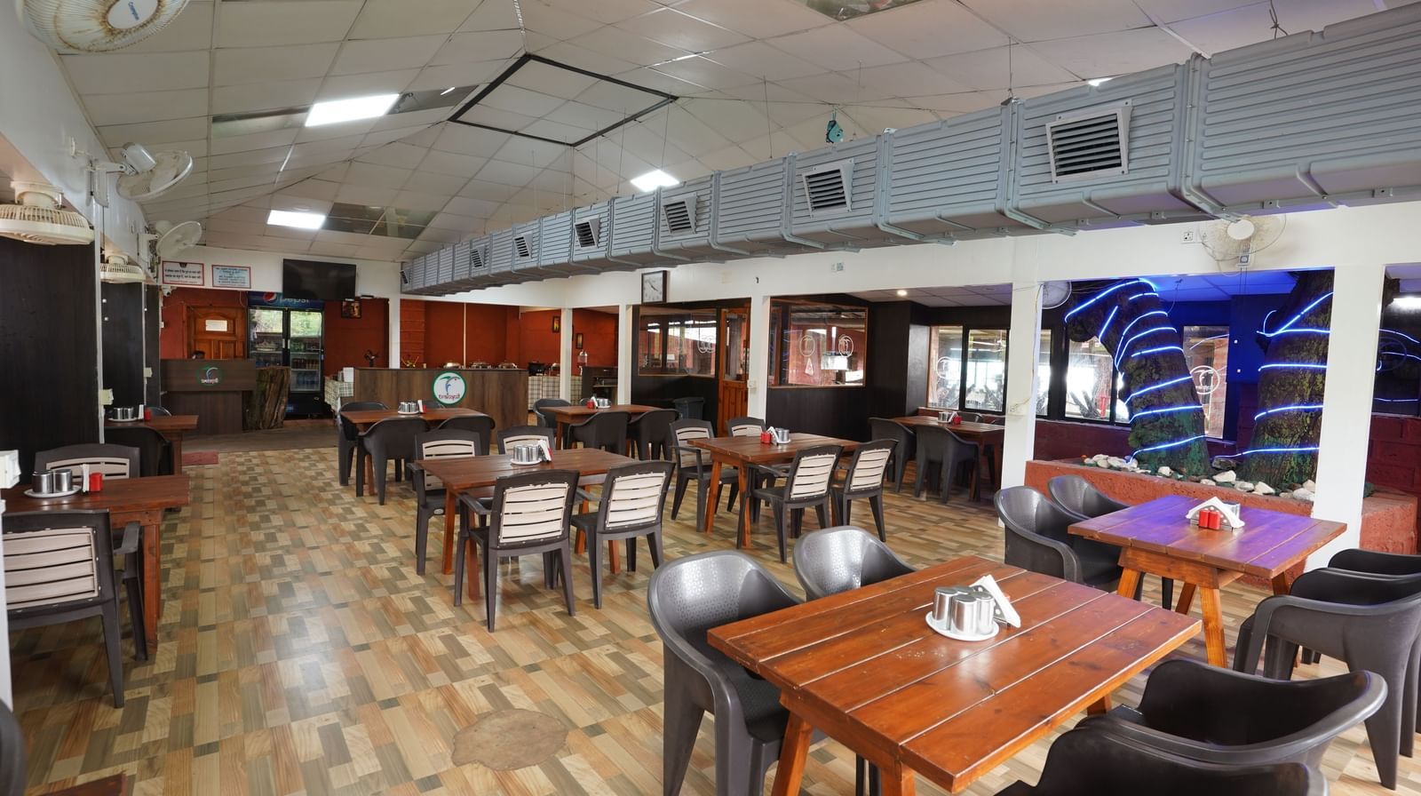 Indoor restaurant with wooden tables and chairs, featuring a spacious layout - Tranquil Beach Resort, Harihareshwar