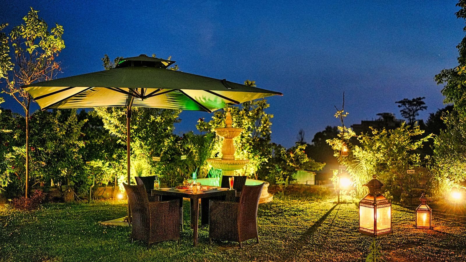 An image of outdoor seating area with umbrellas and plants, captured in the evening.