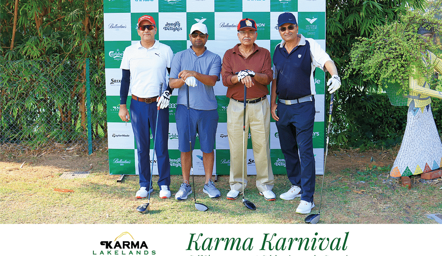 Four men in golf outfits and sunglasses posing in front of the Karma Karnival backdrop