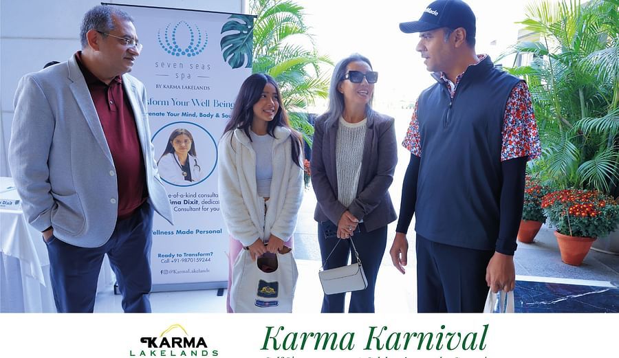 A group conversing near a promotional stand at the Karma Karnival event, dressed in casual attire.