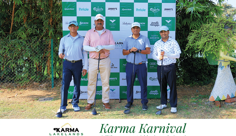 Four men posing with awards and golf clubs in front of the branded Karma Karnival backdrop.