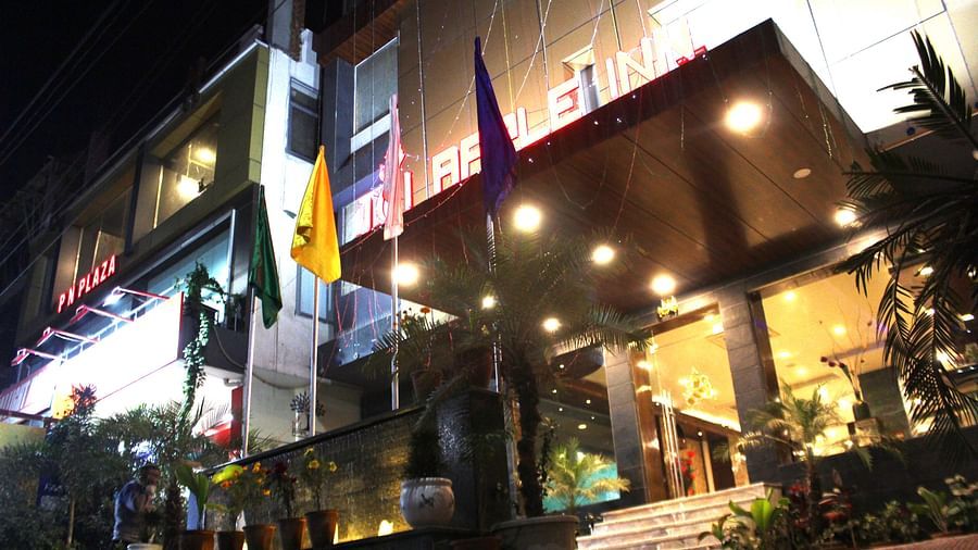 A low angle shot of the hotel at night illuminated by yellow and white lights and flags placed at the front - TGI Apple Inn, Jaipur 