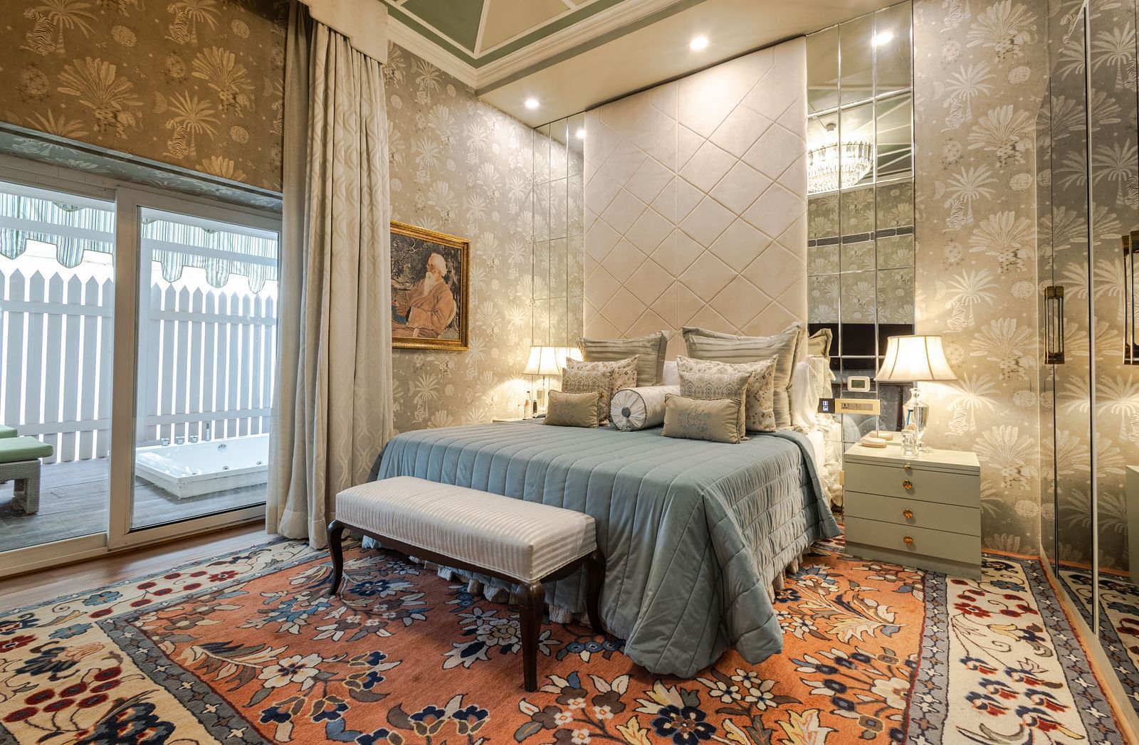 Luxury Suite with Whirlpool at The Claridges New Delhi, featuring a cosy bed with bedside lamps, a table at the foot of the bed, and a large window