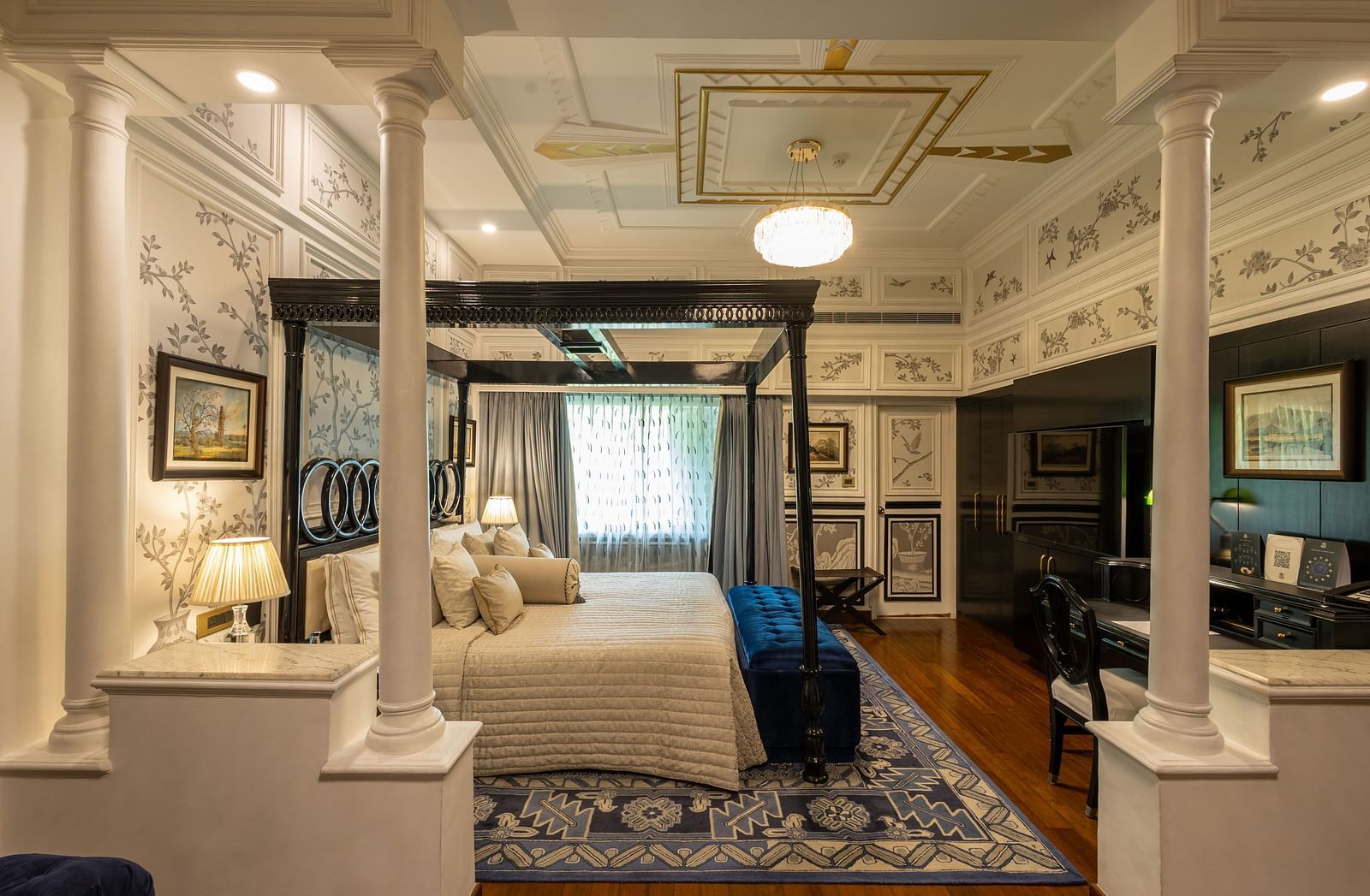 Grand Luxury Room at The Claridges New Delhi, showcasing a side view of the canopy bed with a bedside lamp and a chandelier