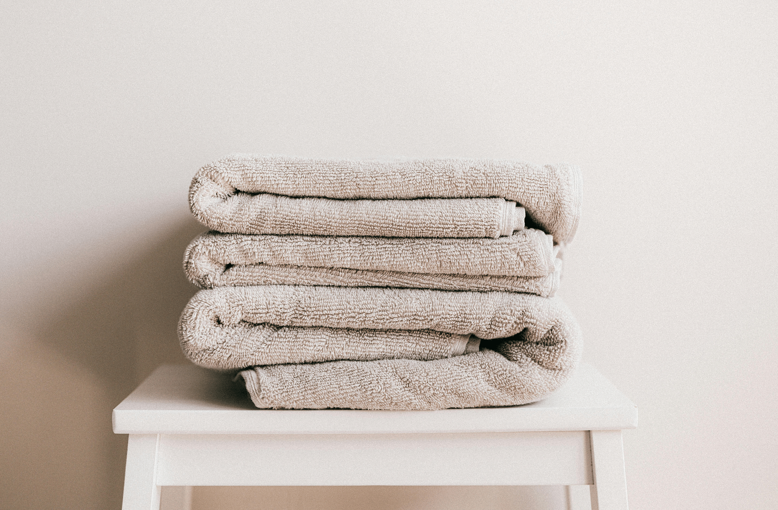 image of clean white coloured towels neatly folded and kept on a white stool