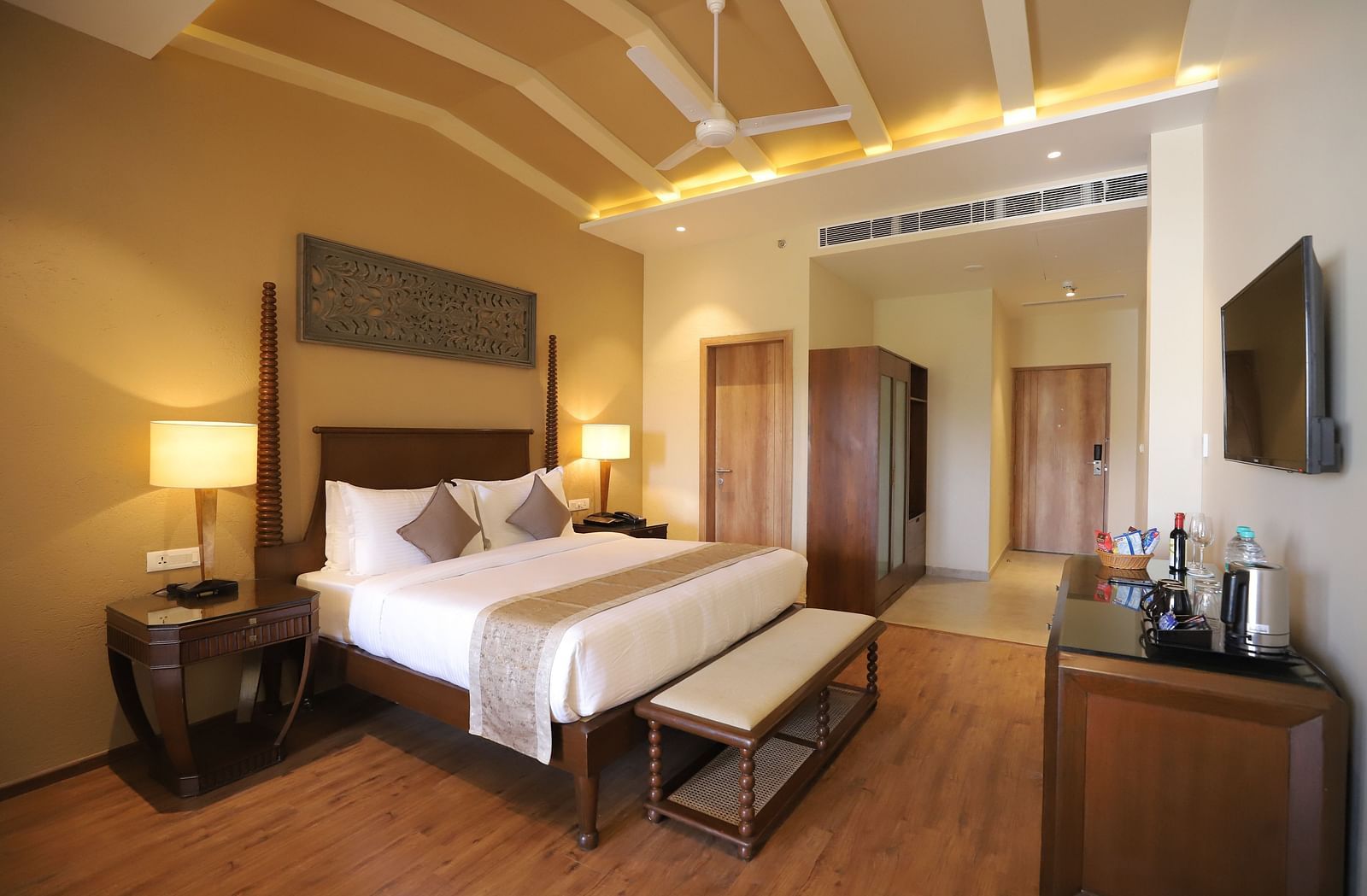 Deluxe room with a king size bed placed in front of a TV at Essentia Luxury Resort & Spa, Udaipur.