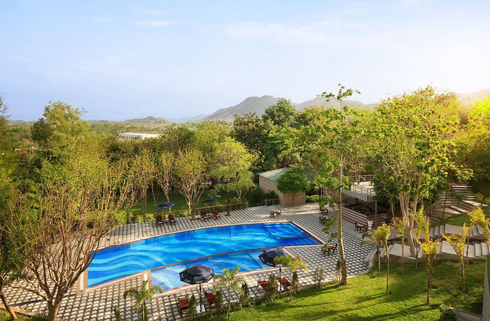 A far out view of the swimming pool surrounded by trees - Essentia Luxury Resort & Spa, Udaipur