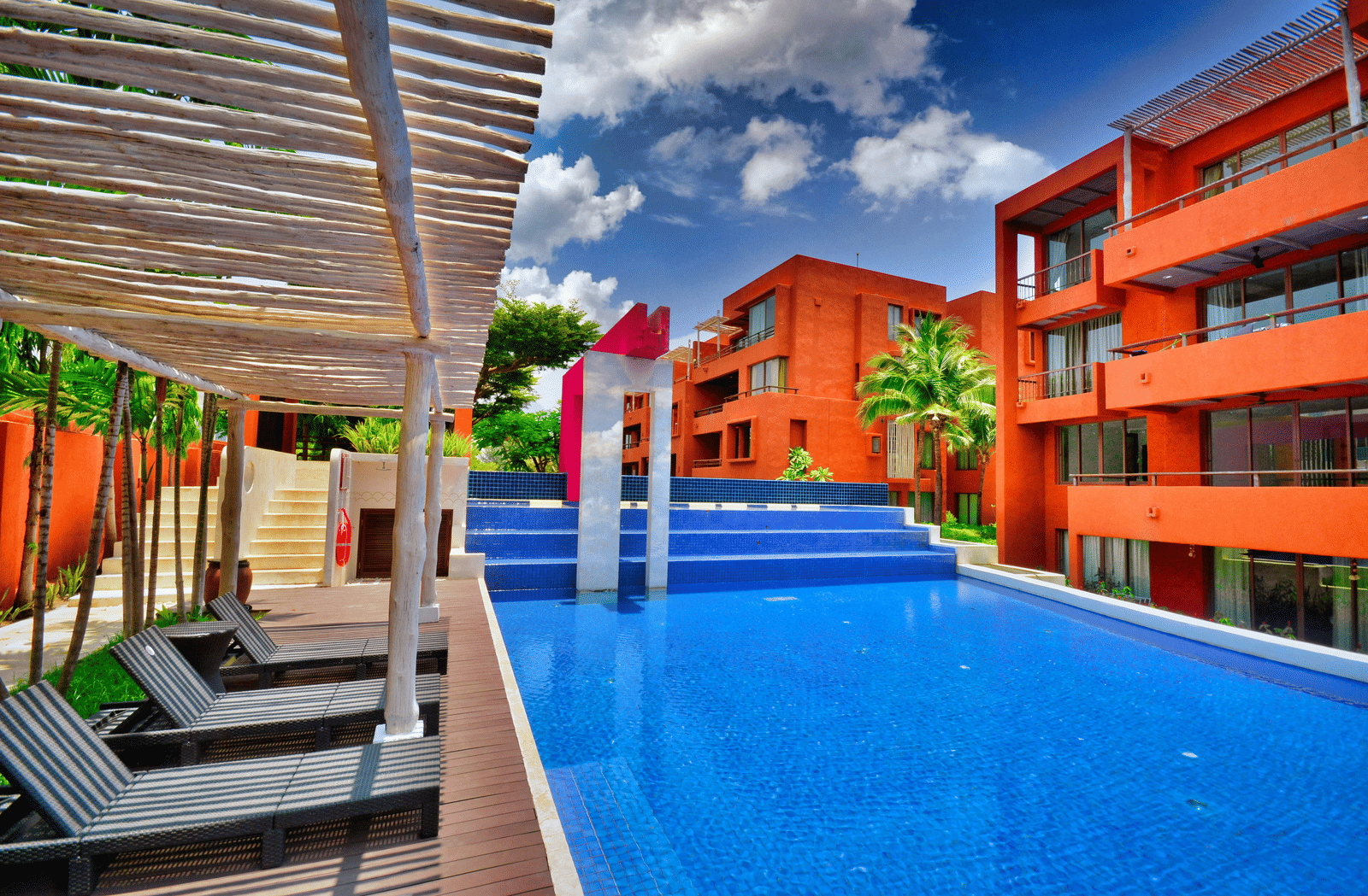 Vibrant hotel facade featuring sun loungers and a pool.