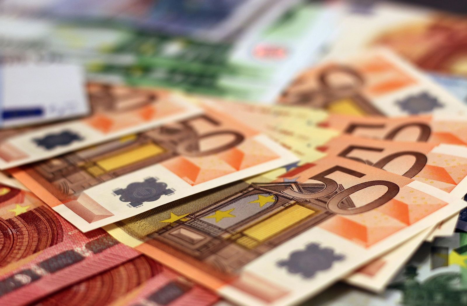 A close up shot of Many Fifty Euro bills placed on a table