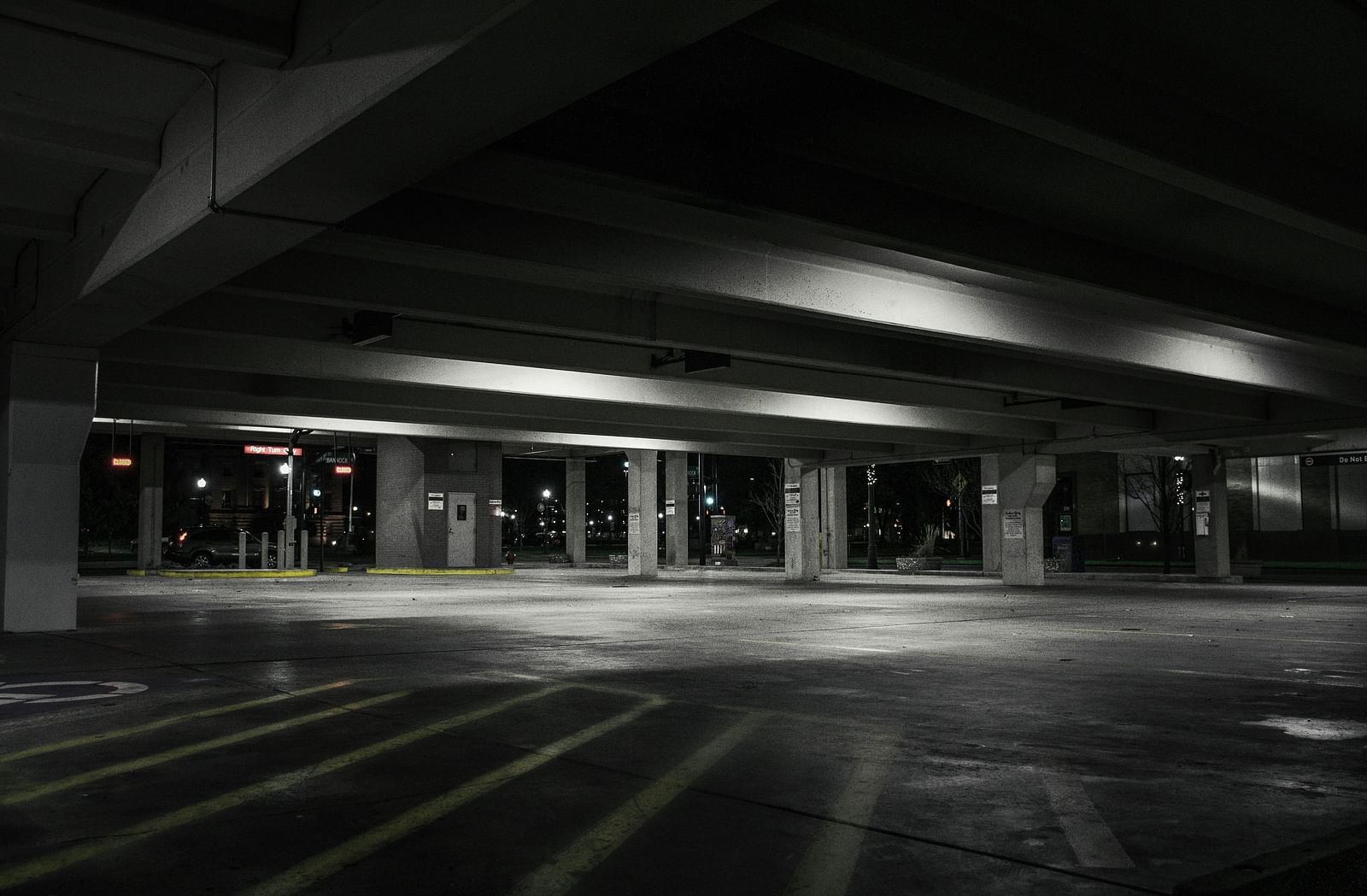 A black and white image of an empty parking lot with the lights on