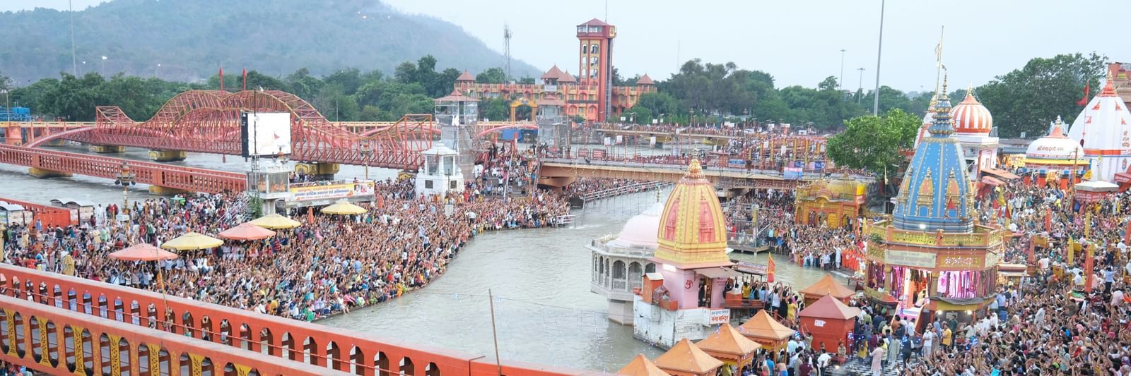 A view from the top of Har ki Pauri in Haridwar with people standing near the ghat section of the ganga river.