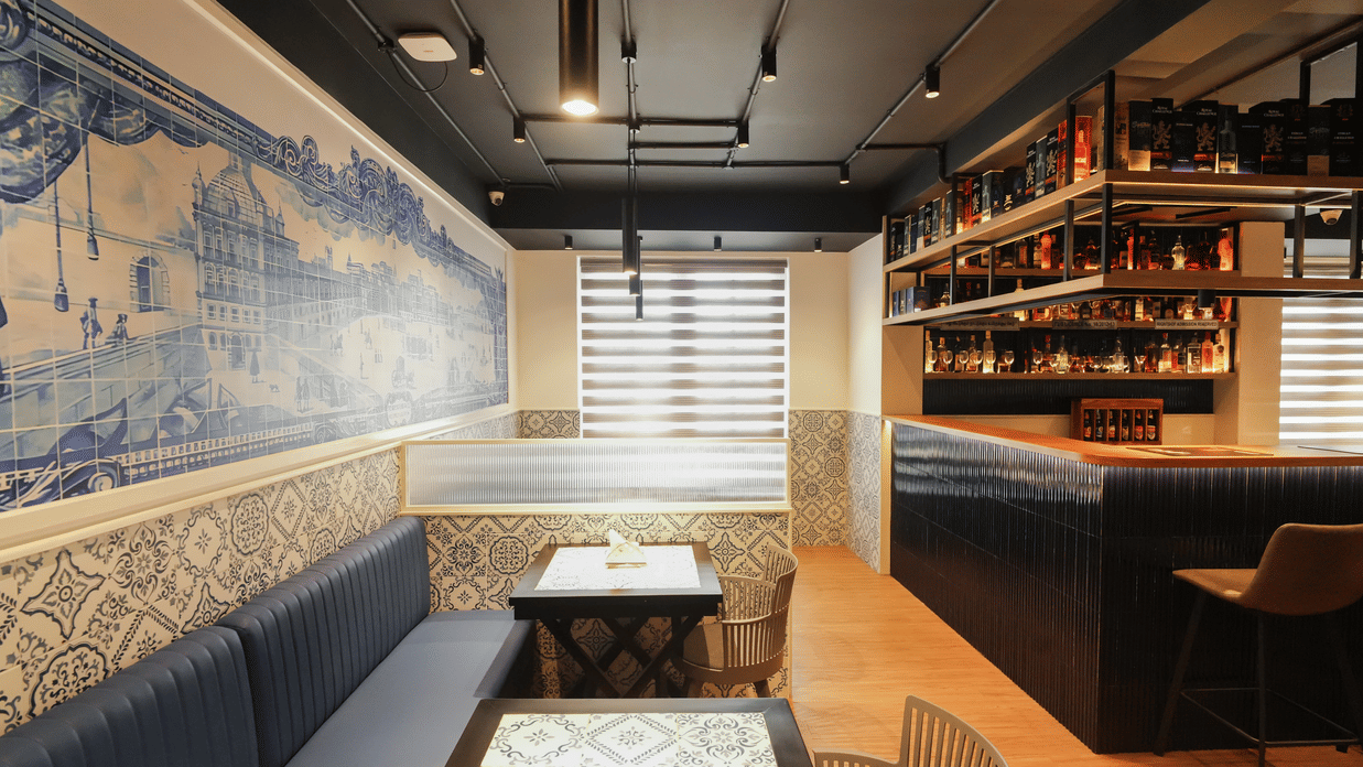 Enclosed dining corner at MGM Vailankanni Residency with cushioned seating, low tables, and a mural along the wall.