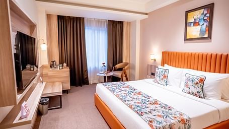 Superior Room at ASTER GRAND BY ZENQ SAKET with a bed, bed side table, TV, a chair and a window with curtain in the background.