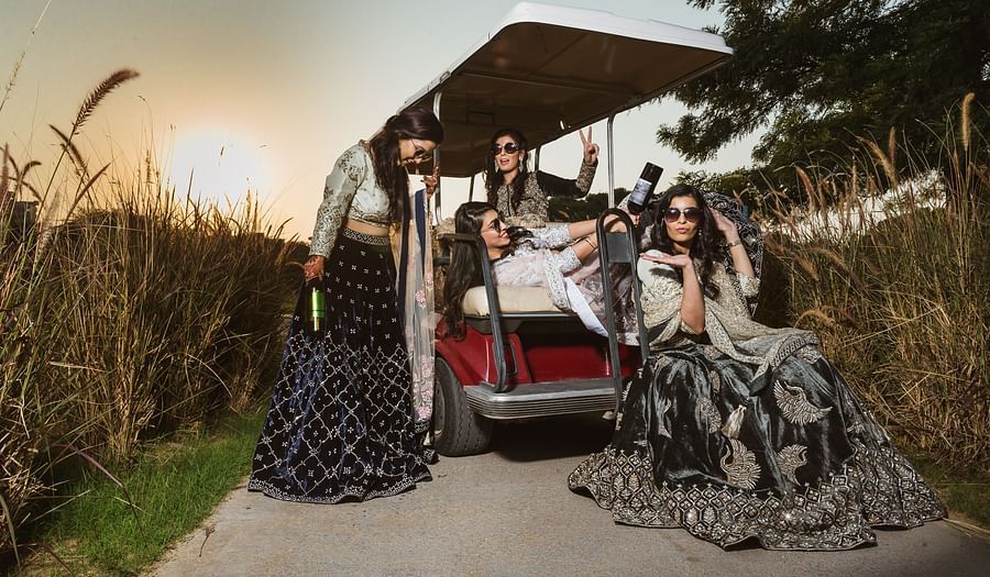 four women posing for a picture on a swing with the sun in the background - Karma Lakelands.
