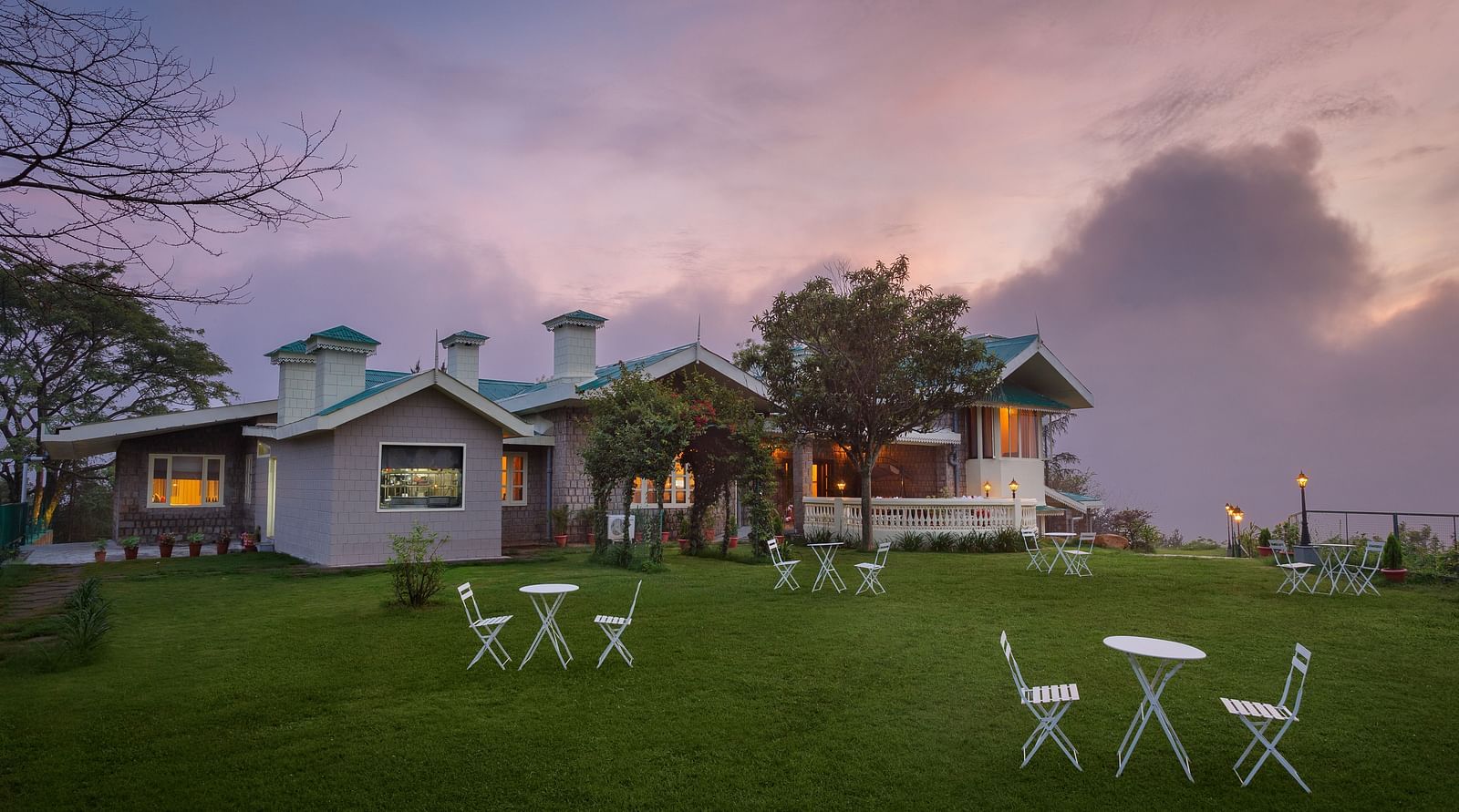 A outdoor picture of the property with the lawn in the front with a few tables and chairs arranged
