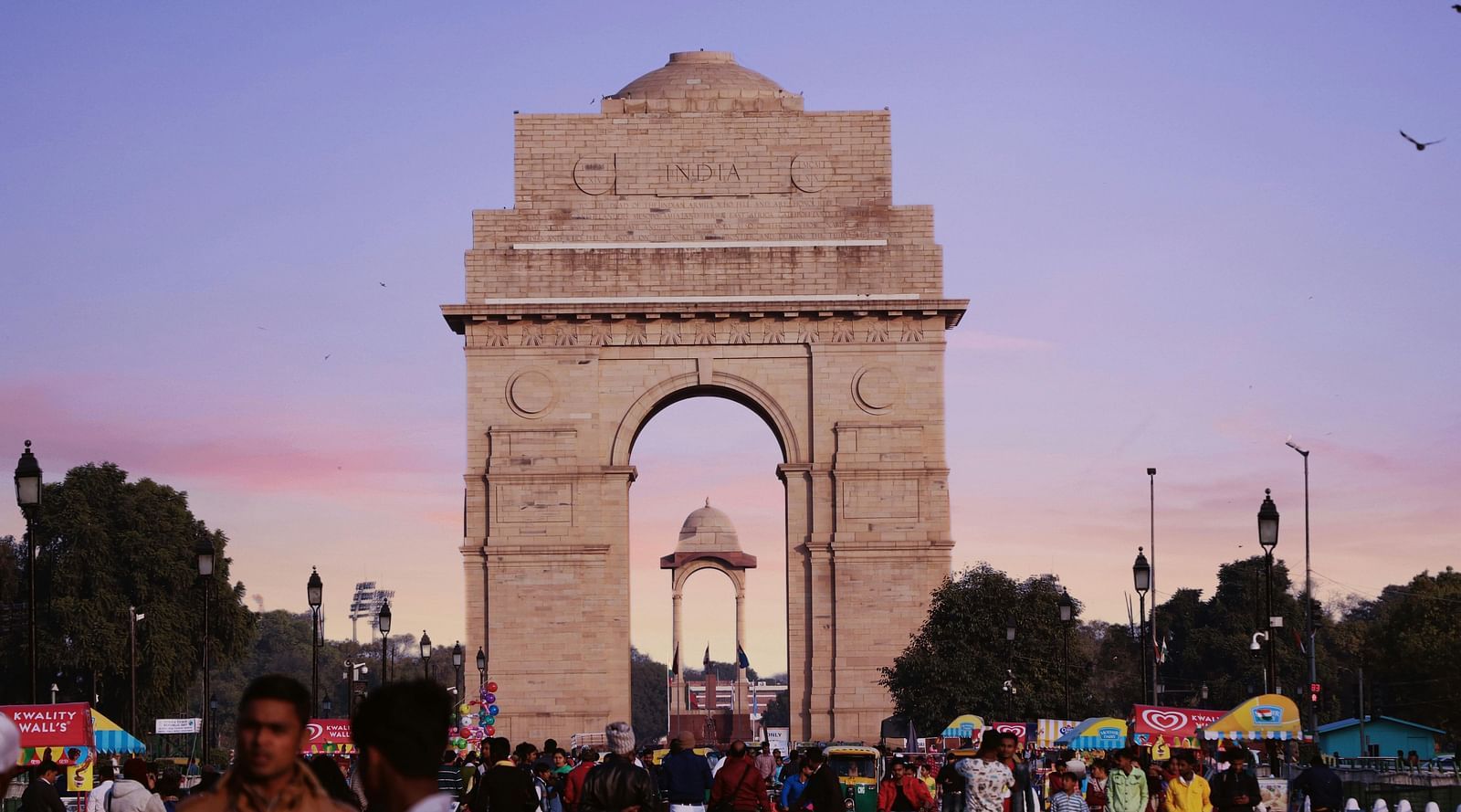 a beautiful image of the india gate monument featuring the amar jawan on a brigh evening with lavender skies in the background