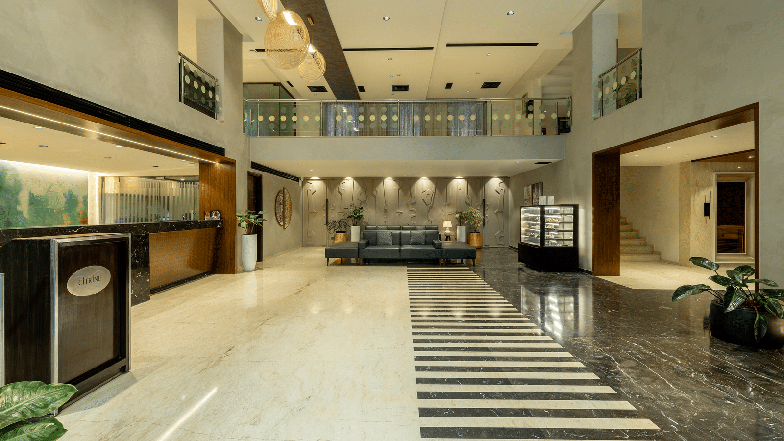 A wider view of the lobby and reception area at the Citrine Hotel, with a staircase leading to an upper floor.
