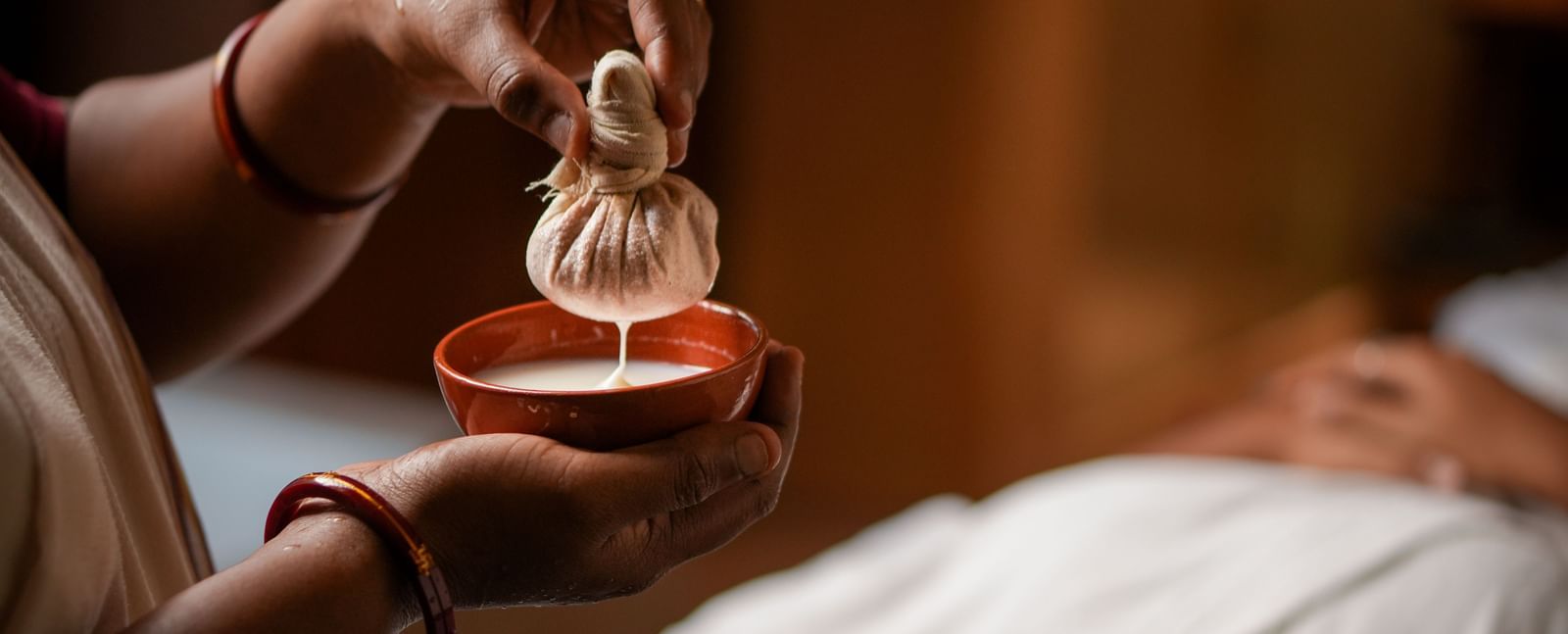 Herbal compress therapy in Vedic Village Spa Resort, featuring a warm poultice being prepared.