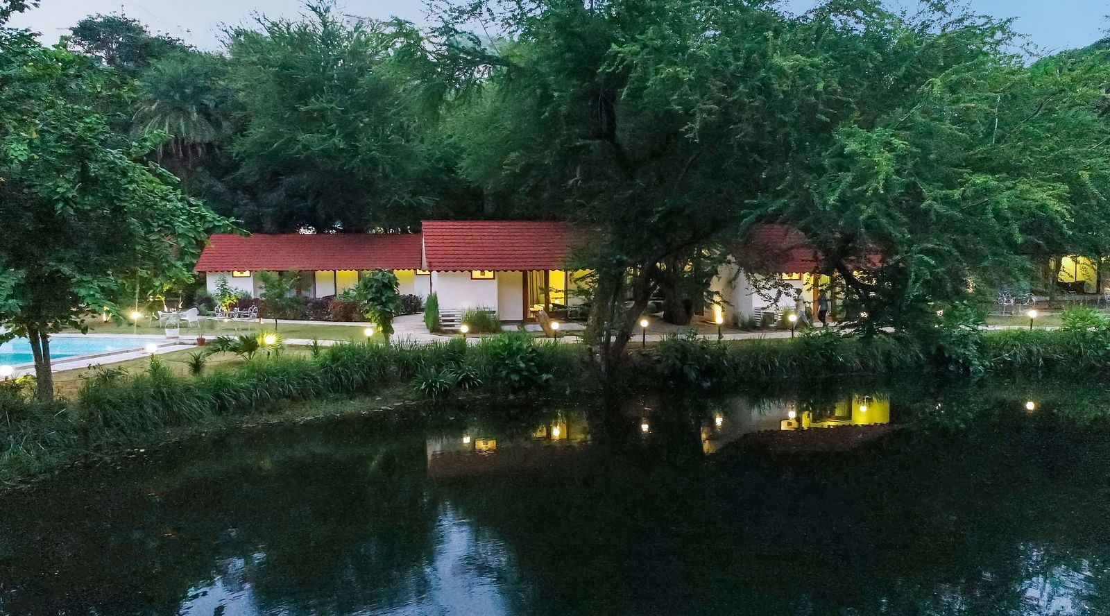 full view of the pond in front of the luxury pond view villa amidst lush green trees at aranya vilas