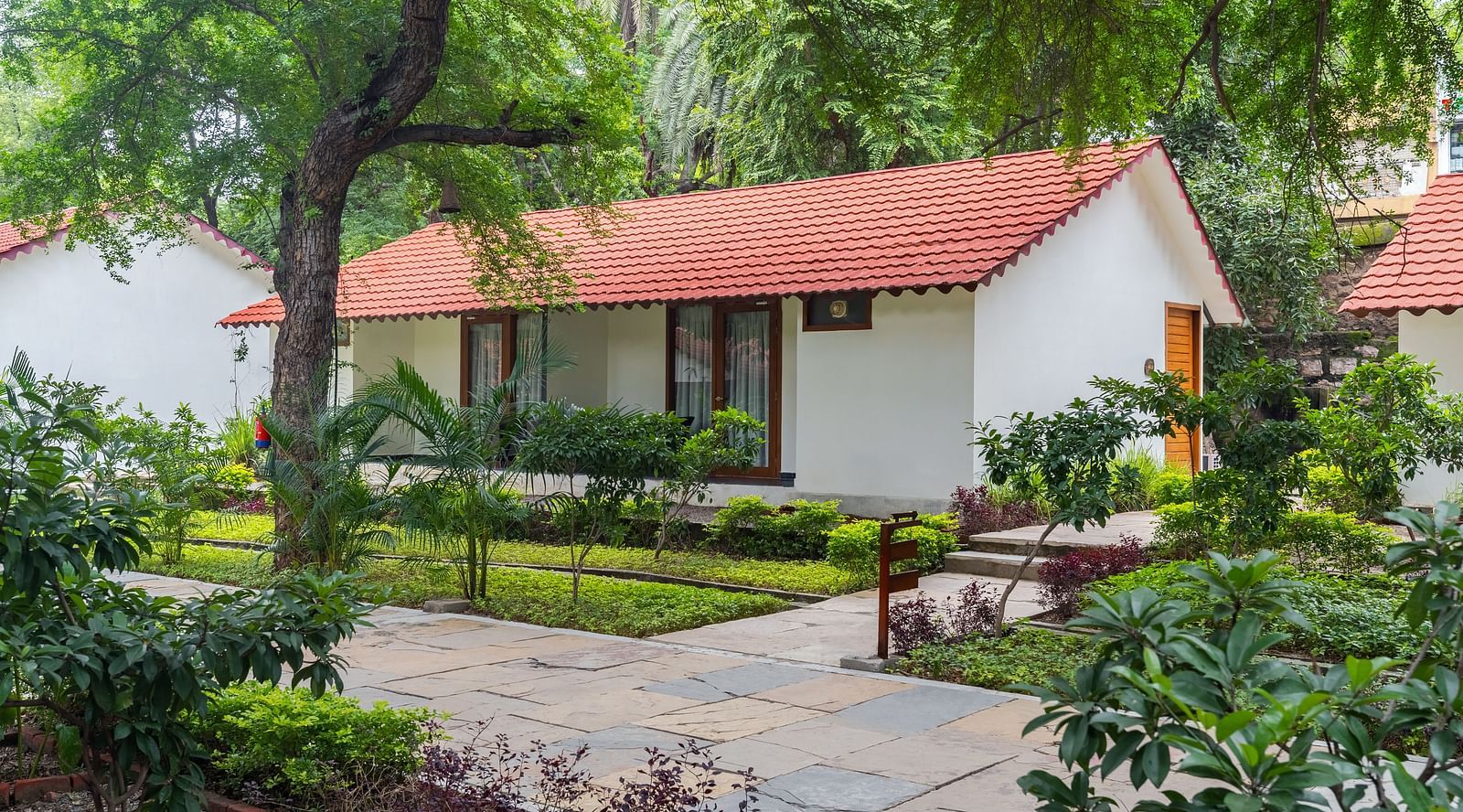 facade image of the luxury villa nestled amidst lush greenery with a private lawn outside the villa
