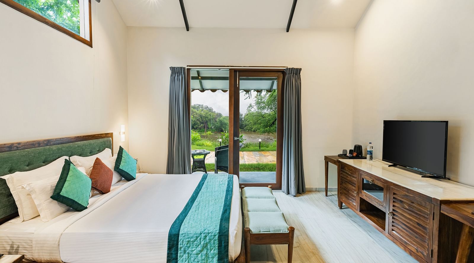 image of a plush king size bed and a full size french windows at the luxury pond view villa at aranya vilas