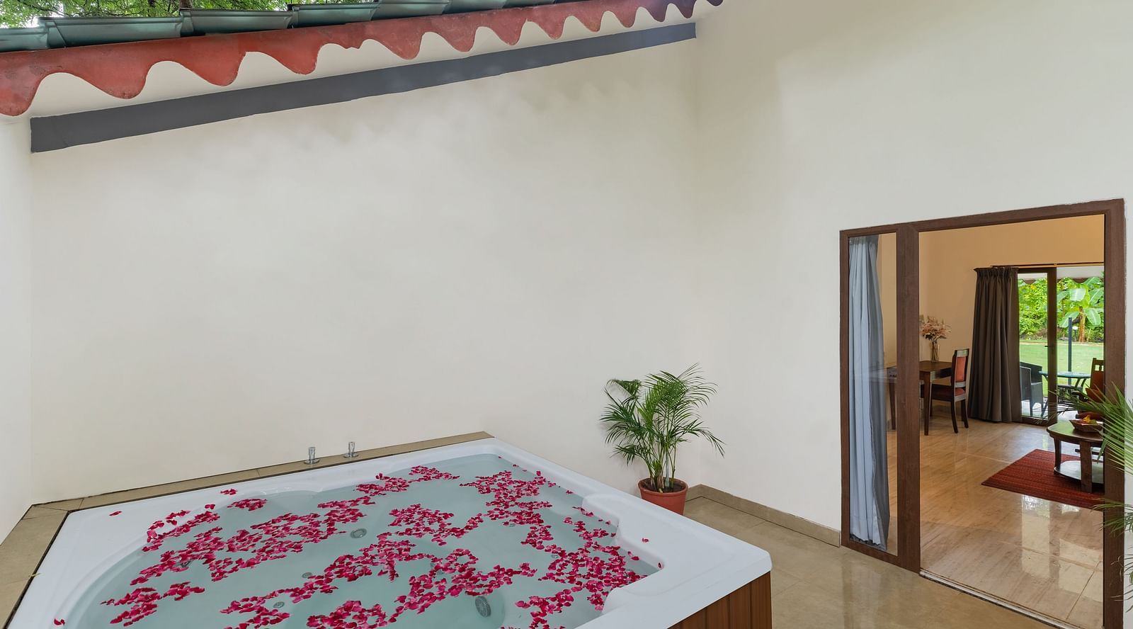corner view of the outdoor Jacuzzi bath with rose petal floating on the water with the entrance to the suite at the far corner at aranya vilas in udaipur