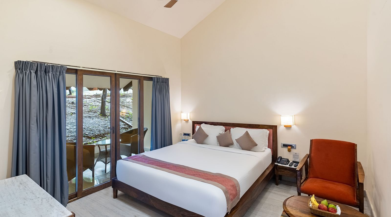 image of the bedroom at the luxury family suite featuring a plush king size bed with huge french windows besides it adorned with blue drapes at aranya vilas in udairpur