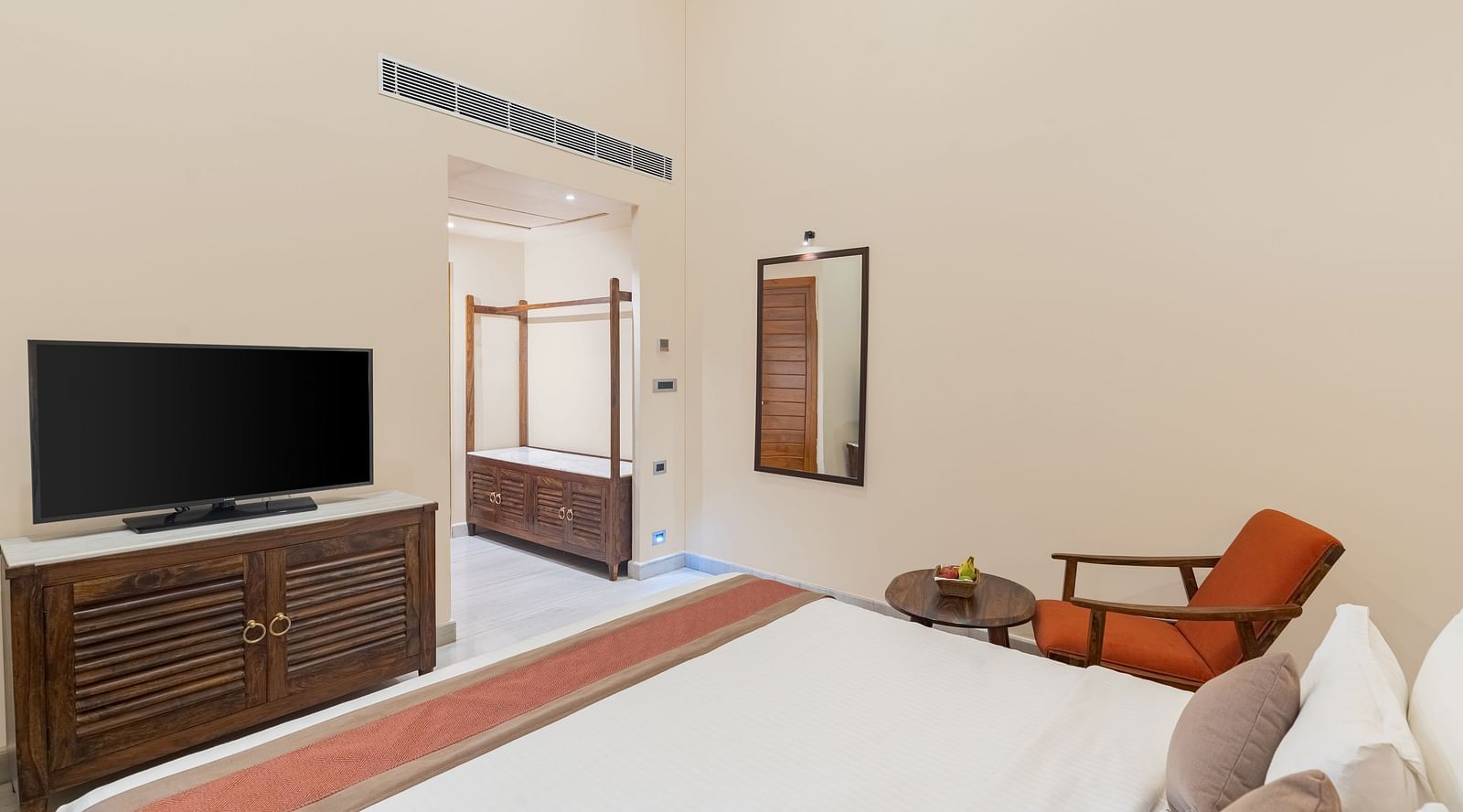 image of the bedroom showcasing a king size bed along a television with the tv table opposit to it with a cushioned arm chair at the luxury family suite in aranya vilas in udaipur