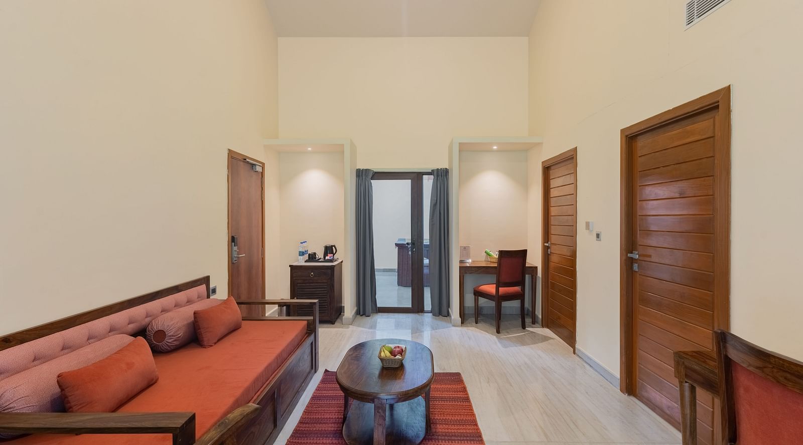 image of the separate living area featuring a a couch and a centre table  with doors leading to other bedrooms at the luxury family suites in udaipur